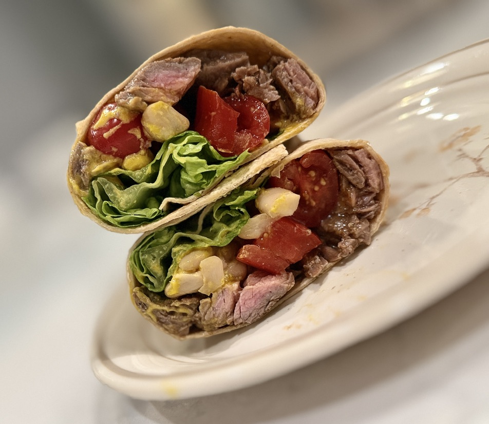 Sliced steak wrap with tomatoes, lettuce, corn, and avocado